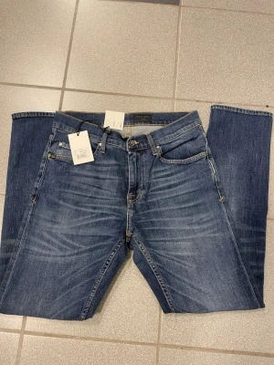 Tiger of Sweden blå jeans  - Snygga blå jeans från Tiger of Sweden med klassisk femficksdesign och raka ben. Jeansen har en mörk tvätt med lätt slitning och smal fot. Passar dig som gillar stilrena och tidlösa jeans med skön passform.