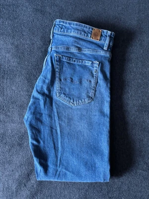 Replay Slim Jeans Marty W30 L30 - Snygga blå jeans från Replay med klassisk femficksdesign och raka ben. Jeansen har en ljus tvätt och är tillverkade i mjukt denimtyg. Perfekta för en avslappnad och stilren look.