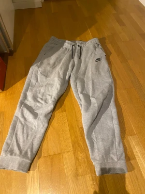 Nike tech fleece byxor - Säljer nu dessa Nike tech byxor då de är väldigt små för mig. De är i storlek 158-170cm. Dem är i ett bra skick förutom att det är lite nopprigt vid Nike loggan (se på bild 2). Tveka inte på att höra av dig vid funderingar
