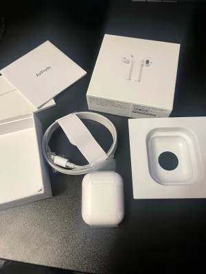 Apple AirPods 2 med laddningsetui - Säljer ett par vita Apple AirPods 2 med trådlöst laddningsetui. Klassisk stilren design i blank plast, smidig passform och enkel anslutning till iPhone. Originalförpackning, laddningskabel och manualer medföljer. Perfekta för musik, samtal och poddar.  1:1 med giltig serienummer 