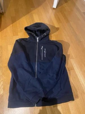 Sail racing hoodie - Säljer nu denna blå/svarta sail racing hoodie pågrund av att den inte passar längre den är i barnstorlek, 170cm. Tveka inte på att höra av dig vid funderingar.