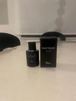Dior Sauvage Elixir parfym - Dior Sauvage Elixir parfym i en elegant mörkblå glasflaska med matchande svart kartong. Flaskan har en stilren, rund form och silverdetaljer vid halsen. En ikonisk doft som utstrålar lyx och modernitet den är typ 20ml kvar