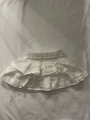 Vit volangkjol med spetsdetaljer - Supersöt vit kortkjol. Jättefint skick och inga defekter. Pris går att diskuteras!