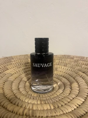 Dior Sauvage Eau de Toilette - Dior Sauvage Eau de Toilette i en stilren glasflaska med svart och transparent design. Flaskan har rund form och tydlig logga framtill. En ikonisk doft som känns modern och fräsch, perfekt för dig som gillar exklusiva parfymer.