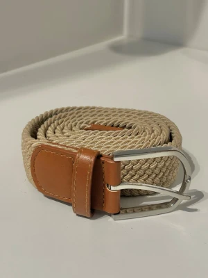 Flätat Bälte - Säljer ett snyggt flätat bälte som är i gott skick 9/10 knappast användt! Det har ett stretchigt material som är rörligt o bekvämt att bära. Hör av er vid frågor eller funderingar!