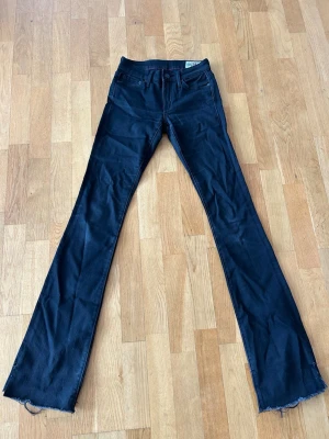 Svarta bootcut jeans från Crocker - Ett par svarta bootcut jeans från Crocker med slitningar nertill. Jeansen är lågmidjade och är tillverkade i ett stretchigt denimtyg som sitter snyggt. Perfekta jeans både till vardags och till festligare tillfällen. 🥰