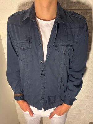 Skjorta med slitningar och tryck - Tja, säljer en fet skjorta med slitningar och tryck på ryggen. Storlek S passar S/M. Skick 8/10, sparsamt använd. Pris 329 men kan diskuteras. Fraktar samma dag, hör av dig vid frågor!