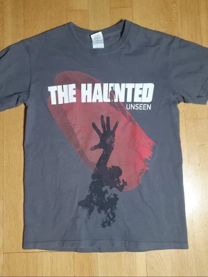 The Haunted (år 2011) T-Shirt | S / Small | Retro Y2K - T-Shirt med The Haunted - Unseen (år 2011) tryck på framsidan och baksidan.  Gildan - Ultra Cotton. Small (Mått finns på bilderna!) 100% bomull.  Se bilder.