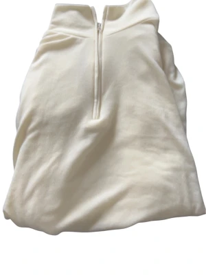 Vit hoodie med halv dragkedja - Stilren vit hoodie med halv dragkedja framtill och hög krage. Tillverkad i mjukt material som känns skönt mot huden. Perfekt för en avslappnad look och enkel att matcha med andra plagg. Inga synliga loggor eller tryck.