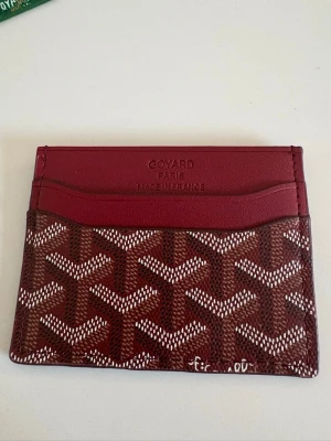 Vinröd korthållare - Snyggt rött korthållare med klassiskt mönster i vitt och rött. Tillverkat i läder med flera kortfack . Perfekt för dig som vill ha en exklusiv och stilren accessoar i fickan. Priset kan diskuteras vid snabb äffär!✅