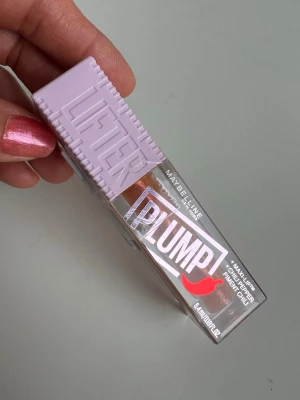 Maybelline Lifter Plump Läppglans volymgivande  - Säljer ett Maybelline Lifter Plump läppglans med chilipeppar-extrakt för extra volym. Färgen är en skimrande orange med guldtoner och glossig finish. Förpackningen är transparent med ljust lila lock och tydlig PLUMP-logga. Perfekt för dig som vill ha fylligare läppar med glans.Detta är ett volymgivande läppglans som innehåller chilipepparextrakt, vilket ger en pirrande eller stickande känsla för att visuellt göra läpparna fylligare. Den innehåller även hyaluronsyra för återfuktning.   