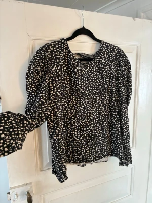 Svartvit långärmad tröja från Kappahl XL - Snygg svartvit långärmad tröja från Kappahl i storlek XL. Tröjan har ett prickigt mönster, långa puffärmar och rund halsringning. Perfekt för dig som gillar trendiga detaljer och vill sticka ut lite extra.