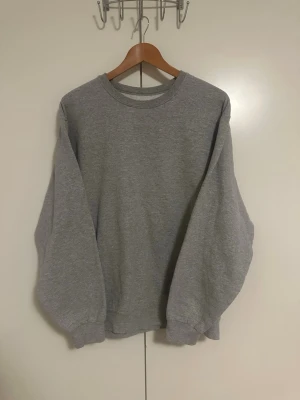 Vintage Grå basic sweatshirt unisex - Enkel och stilren grå sweatshirt med rund hals och ribbade muddar vid ärmslut och nederkant. Oversized passform som passar både tjejer och killar. Perfekt att matcha med jeans eller mjukisbyxor för en avslappnad look.