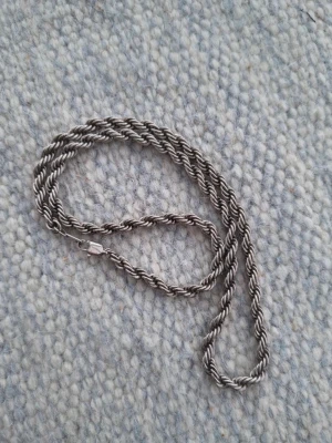 Tvinnat silverfärgat halsband - Säljer ett stilrent halsband i tvinnad design med silverfärg. Halsbandet är cirka 45 cm långt och har en enkel låsning. Perfekt för dig som gillar minimalistiska smycken med en twist.