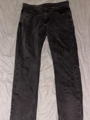 Svarta Levi's slim fit jeans - Säljer ett par svarta Levi's jeans med klassisk slim fit och fem fickor. Jeansen har en diskret tvättad look och är tillverkade i slitstark denim. Passar perfekt till en avslappnad stil och har den ikoniska läderlappen bak i midjan.