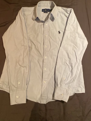 Ralph lauren skjorta - Säljer denna mycket fina Ralph lauren skjortan till ett mycket fint pris. Den är använd ett par gånger. Men strycker man till den så kommer den se helt oanvänd ut för det finns inga fläckar eller så på den. Tveka inte för att skriva om du skulle ha några frågor.