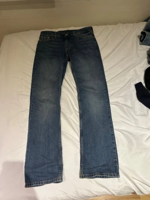 Blå bootcut jeans från Levi's - Klassiska blå jeans från Levi's 527 med bootcut passform och fem fickor. Jeansen har en snygg tvättad look och är tillverkade i slitstark denim. Perfekta för dig som gillar en tidlös och avslappnad stil. 