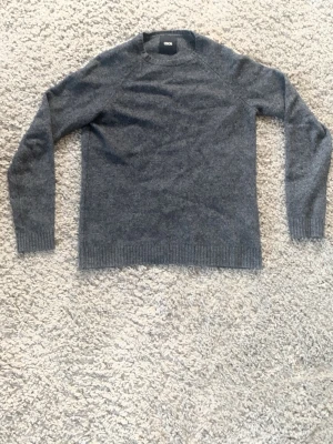 Mörkgrå stickad tröja från ASOS - Mysig mörkgrå stickad tröja från ASOS med rund halsringning och ribbade muddar vid ärmslut och nederkant. Perfekt för lager på lager och enkel att matcha med olika stilar. Tillverkad i mjukt material som känns skönt mot huden. Perfekt nu till våren!