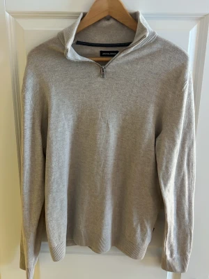 Beige halvzip-tröja från Jack & Jones - Stilren beige tröja från Jack & Jones med halvzip och hög krage. Tillverkad i mjukt stickat material. 