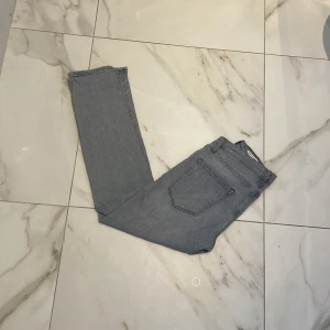 Jack&Jones ljusgråa jeans  - Säljer ett par ljusgrå jeans med rak passform och klassisk femficksdesign storleken är M på denna men passar även S beroende på passform. Jeansen har bälteshällor och är sydda i ett mjukt denimtyg. Perfekta för en avslappnad och stilren look.