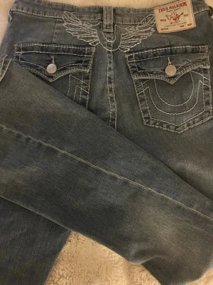 Blå True Religion Jeans stl 31 - Aldrig använda då dem va lite stora i midjan. Inga skador, köpta för 1 månad sen.Nypris 1500kr. Pris kan diskuteras, går inte under 900kr. Kan byta mot andra jeans stlk 24-23. 
