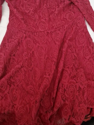 Vinröd spetsklänning med lång ärm - Supersnygg vinröd klänning i spets med långa ärmar och blommigt mönster. Klänningen har en figurnära passform upptill och utställd kjol. Perfekt för dig som vill sticka ut med en elegant look. PRIS KAN DISKUTERAS