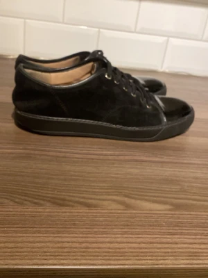 Svarta Lanvin sneakers - Billiga grisch pjucks perfekta för en dag på stureplan. Skorna är tillverkade i svart mocka med lackad tå. Billiga priset pågrund av slitningarna på under sulan annars ett par helt okej lanvins✌️