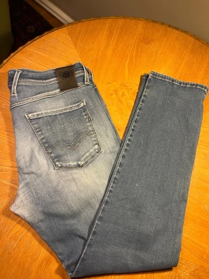 Replay Blå slim fit jeans  - Snygga blå slim fit jeans från Replay med klassisk femficksdesign och ljus tvätt. Jeansen har en skön stretchig bomullsblandning och detaljerade sömmar på bakfickan. Perfekta för en avslappnad och trendig look. Storlek: W34 L30 