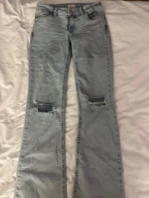 Low Waist Perfect Bootcut Jeans Nelly - Säljer ett par ljusblå bootcut low waist jeans med rosa detaljer från Nelly. Säljer för att de ej passar längre men de är inte använda så jätte mycket. Jeansen är i bra skick och är storlek 36.