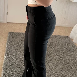 Svarta kostymbyxor från Gina Tricot - Snygga svarta kostymbyxor från Gina Tricot med lång midja och en elegant passform. Byxorna har en klassisk design med utsvängda ben och diskreta fickor. Perfekta för en stilren look💕(priset kan diskuteras)