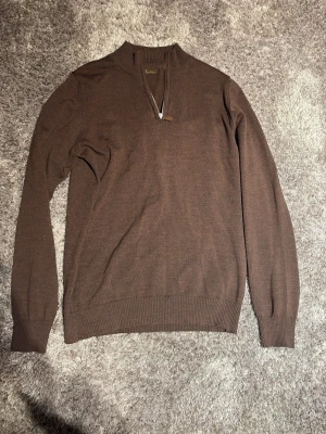 Brun stickad tröja med halv dragkedja - Snygg brun stickad tröja från Stenströms med halv dragkedja och ribbade muddar vid ärmslut och nederkant. Tröjan har en klassisk passform och är perfekt för lager på lager. Materialet känns mjukt och bekvämt.