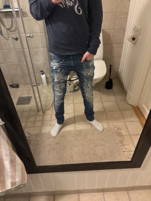 Replay Anbass  - Säljer ett par blå skinny jeans med slitningar och trasiga detaljer framtill. Jeansen har en tvättad look och synliga sömmar, samt bakfickor med slitningar. Jag är 183 cm lång och väger 60kg 