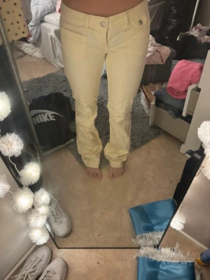Ljusgula bootcut jeans med fickor - Snygga ljusgula jeans med bootcut och klassiska fickor fram och bak. Jeansen har normal midja och stängs med knapp och dragkedja. Perfekta för dig som vill sticka ut med en fräsch färg i garderoben.