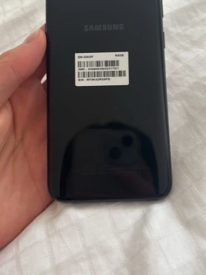 Svart Samsung Galaxy Android-telefon - Snygg svart Samsung Galaxy med stilren design och rundade kanter. Telefonen har en slät baksida i glas och tydlig Samsung-logga. Perfekt för dig som vill ha en pålitlig Android-mobil med modern look och bra känsla i handen.