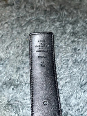 Brunt Louis Vuitton bälte med monogram - Säljer ett brunt Louis Vuitton bälte i skinn med klassiskt LV-monogram i beige och guldigt LV-spänne. Bältet har en bred design och är perfekt för att lyfta vilken outfit som helst med sin ikoniska look.