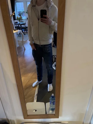Vit cardigan från Paul & shark - Säljer en stilren vit pufferjacka med huva och dragsko. Jackan har två dragkedjeförsedda fickor framtill, ribbade muddar och quiltad insida. Materialet är en mix av glansig polyester och stickad bomull på ärmarna. Perfekt för kalla vinterdagar.