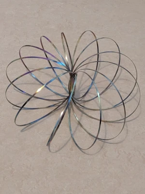 Metall flow ring leksak - Säljer en flow ring i metall som kan användas som stressleksak eller för tricks. Den är silverfärgad med en skimrande yta och består av tunna metallringar som formar en spiral. Perfekt för att roa sig eller visa coola rörelser.