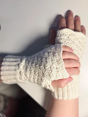 Vita virkade fingerlösa torgvantar - Säljer ett par vita virkade fingerlösa vantar med ribbad mudd och snyggt strukturmönster. Perfekta för dig som vill hålla händerna varma men ändå kunna använda mobilen. Pris är för material + arbetstid. Slim fit.