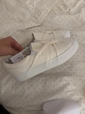 Vita sneakers med knut från Anna Field - Snygga vita sneakers från Anna Field. De är helt oanvända och kommer ej till användning. Skorna är i storlek 36 men passar mig som har 37-38. Hör av er vid fler frågor💗