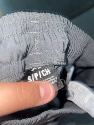 Grå cargobyxor från Under Armour - Snygga grå cargobyxor från Under Armour med elastisk midja och flera praktiska fickor på sidorna. Byxorna har en avslappnad passform och är tillverkade i ett lätt och bekvämt material. Perfekta för en sportig och casual stil.