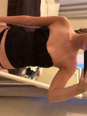 Svart bandeau tubtopp - Säljer en svart bandeau tubtopp. Toppen är axelbandslös och har en tight passform som framhäver figuren. Säljer då förliten. 