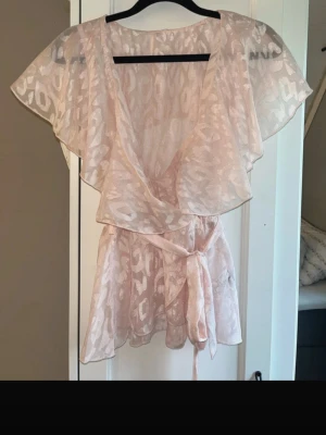 Ljusrosa omlottklänning med knytband - Söt ljusrosa kortklänning med omlottmodell och knytband i midjan. Strl S men passar XS då den är knytbar i midjan. Aldrig använd. SHEIN 