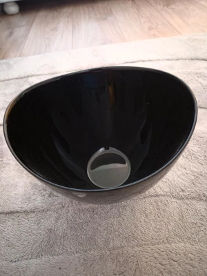 Svart skål i glas - Säljer en stilren svart skål från Orrefors i glas med rundad form och blank yta. Perfekt som inredningsdetalj eller till servering av snacks och godis. Skålen har en modern look och passar bra på soffbordet eller i köket.