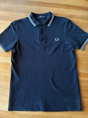 Svart pikétröja från Fred Perry - Fred Perry pike, den är använd några fåtal gånger. Absolut inga hål eller defekter. Tvättad 1 gång så den har kvar den fina piké strukturen. Pris är diskuterbart vid snabbt köp. Tveka inte på att skriva vid frågor. 