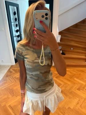 Camouflage topp med kort ärm - Snygg camouflagemönstrad topp med korta ärmar och rund hals. T-shirten har en slim passform och är perfekt för dig som gillar en trendig och avslappnad stil. Passar till både jeans och kjol för en cool vardagslook.