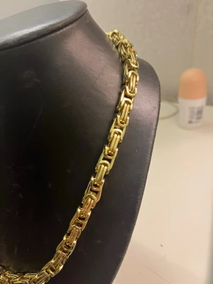 Guldfärgat kedjehalsband - Säljer ett chunky halsband i guldfärg med kraftiga, rektangulära länkar. Halsbandet har en modern och stilren design som verkligen sticker ut. Perfekt för dig som gillar statement-smycken och vill addera lite extra bling till din outfit.