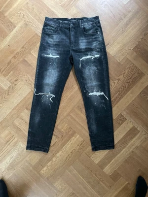 Svarta jeans med slitningar - Säljer ett par svarta skinny jeans från supply & demand med coola slitningar och vit tråd på låren. Jeansen har fem fickor och en tvättad look med lite blekta partier. Perfekta för en edgy streetstil.