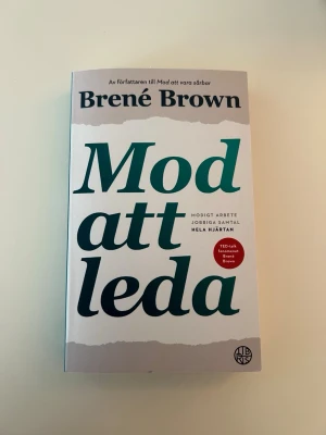 Mod att leda av Brené Brown - En inspirerande bok av Brené Brown om modigt ledarskap, svåra samtal och att våga visa sig sårbar. Pocketbok med vit och beige framsida, grönt och svart tryck. Perfekt för dig som vill utvecklas som ledare och människa.