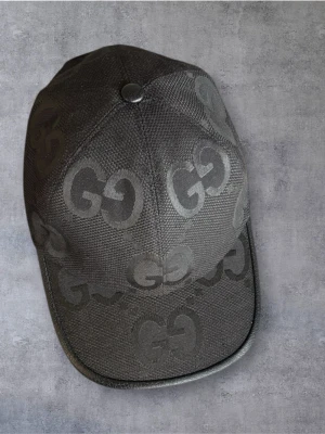 GUCCI KEPS - Snygg svart keps från Gucci med det klassiska GG-mönstret över hela kepsen. Kepsen har böjd skärm och justerbar rem baktill. Materialet är textil med en lyxig känsla och diskret glans. Perfekt för dig som vill ha en stilren accessoar med exklusiv känsla. Inga defekter fint skick!