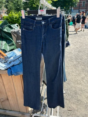 Mörkblå bootcut jeans från ONLY - Snygga mörkblå bootcut jeans från ONLY med klassisk femficksdesign och silverfärgad knapp. Jeansen har en rak passform med lätt utsvängda ben och är tillverkade i denim med stretch för extra komfort.
